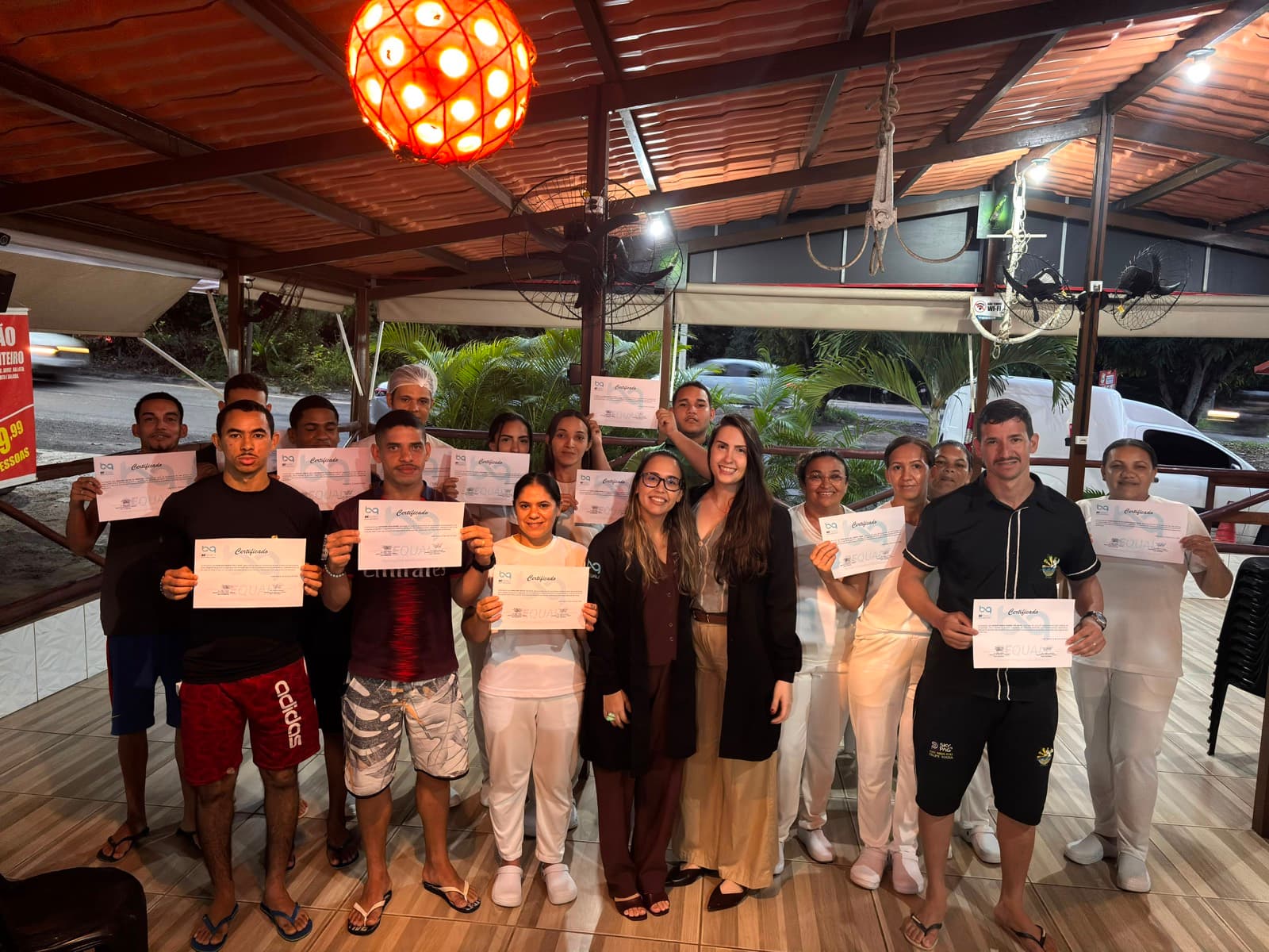 Equipe de restaurante reunida com os certificados ao final do treinamento, na área de atendimento do estabelecimento